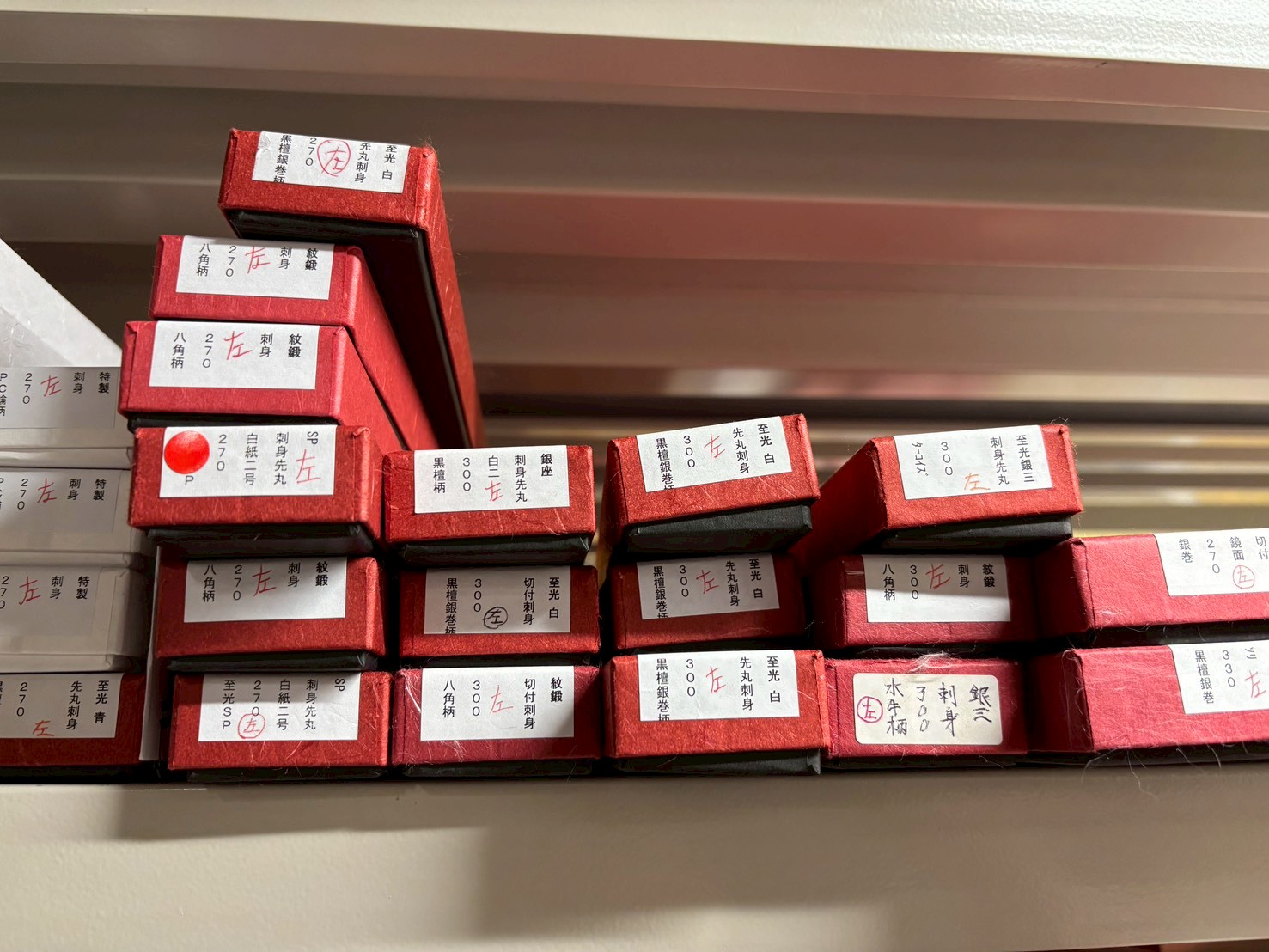 JIKKO店舗に陳列された、豊富な種類の「左利き用」和包丁（出刃・柳刃など）の在庫棚