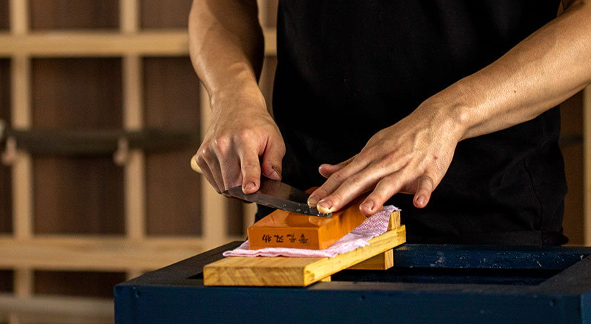 實光（JIKKO）の職人が砥石を使って欠けた包丁を研ぎ直している様子