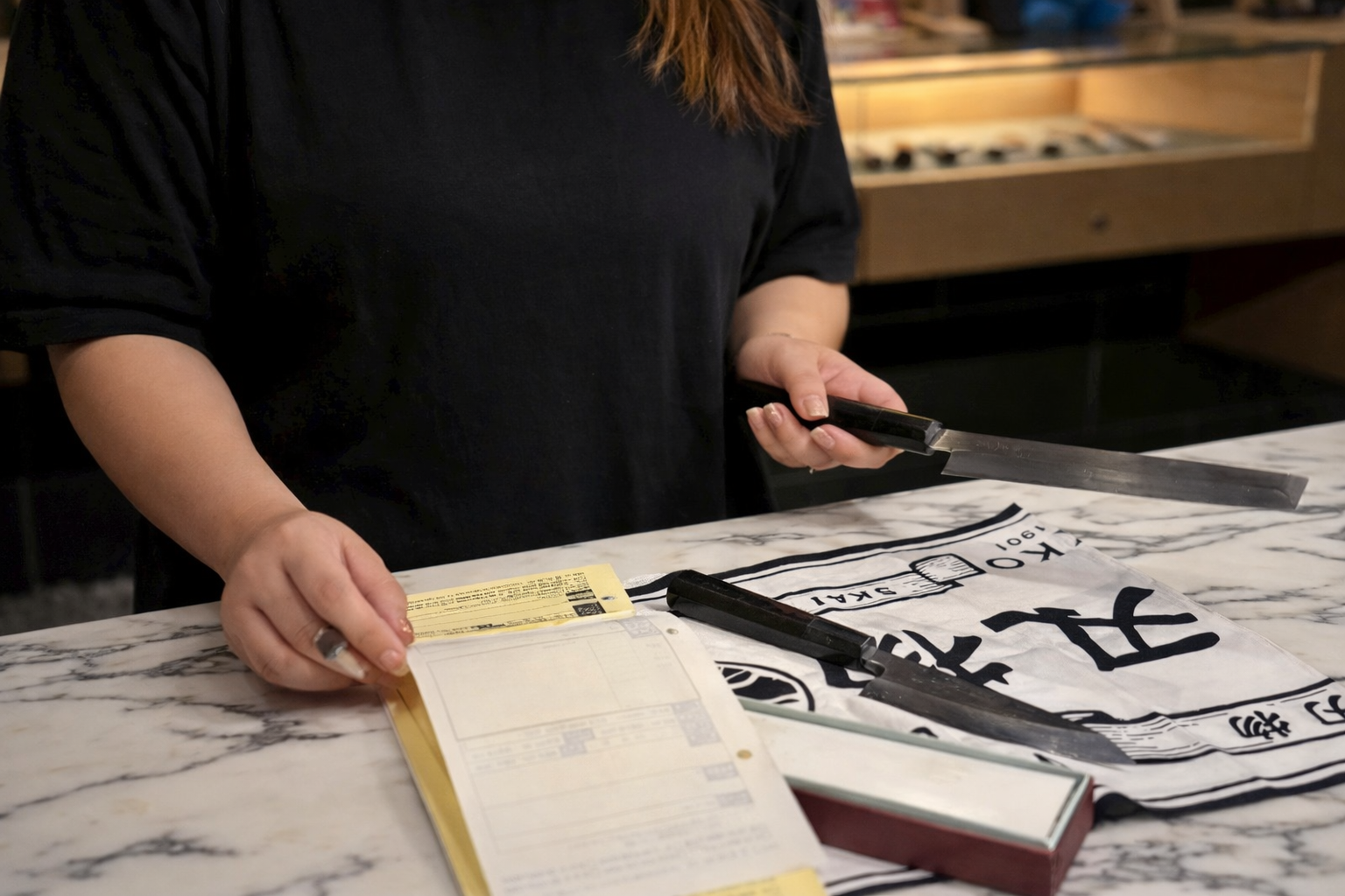 實光刃物の店舗で、研ぎ直しの受付時に包丁を確認しながら相談を受けている様子