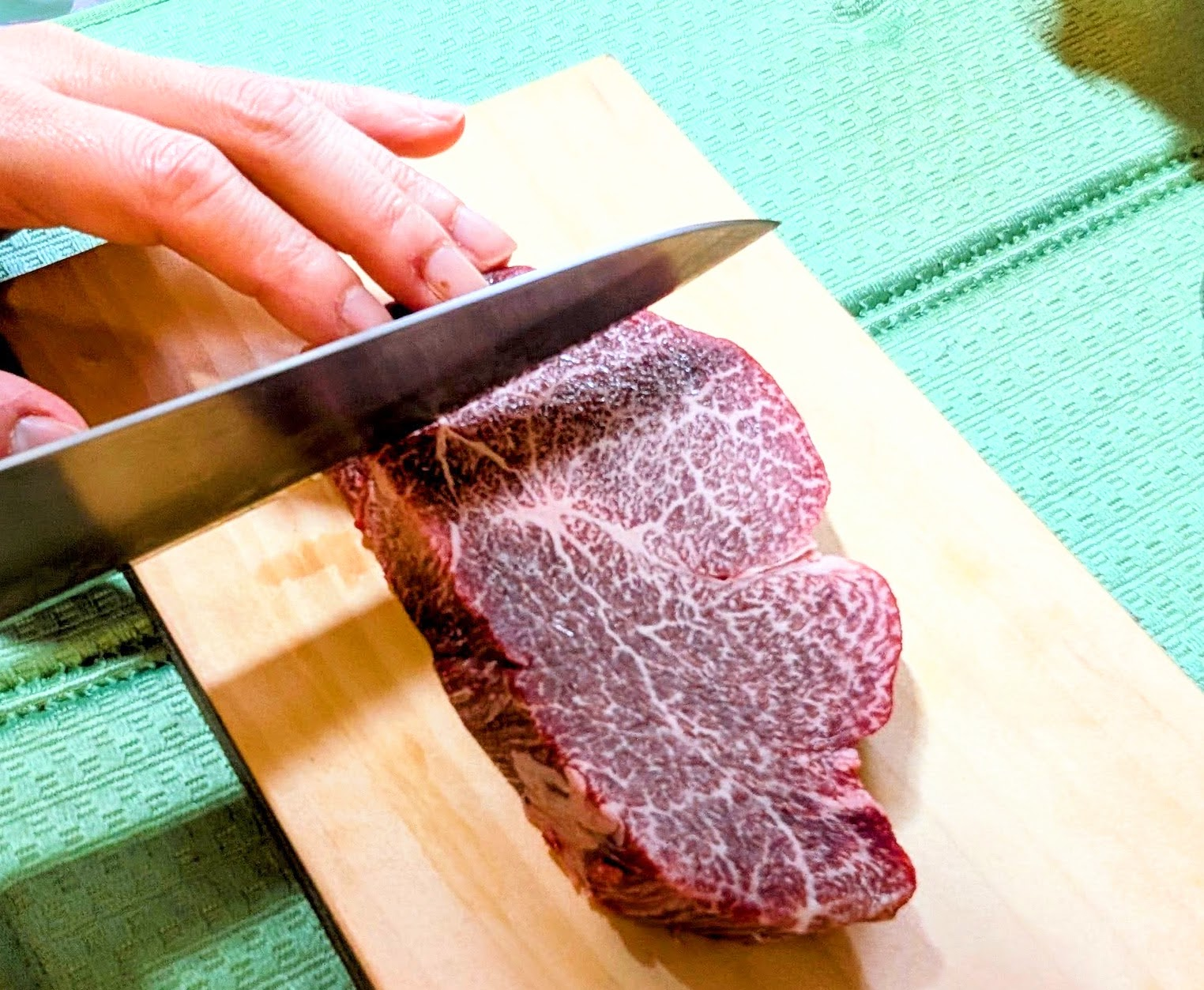 牛刀で肉を切るシェフの手元