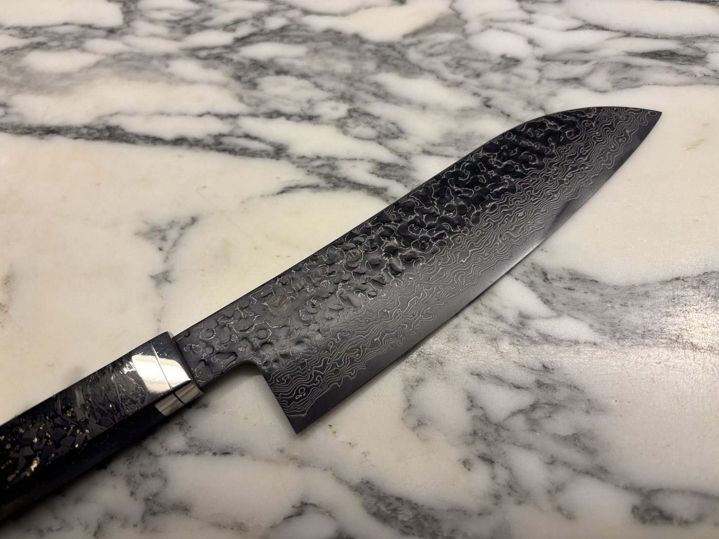 天然石のカウンタートップに置かれた、幾重にも重なる波紋が美しいダマスカス包丁
