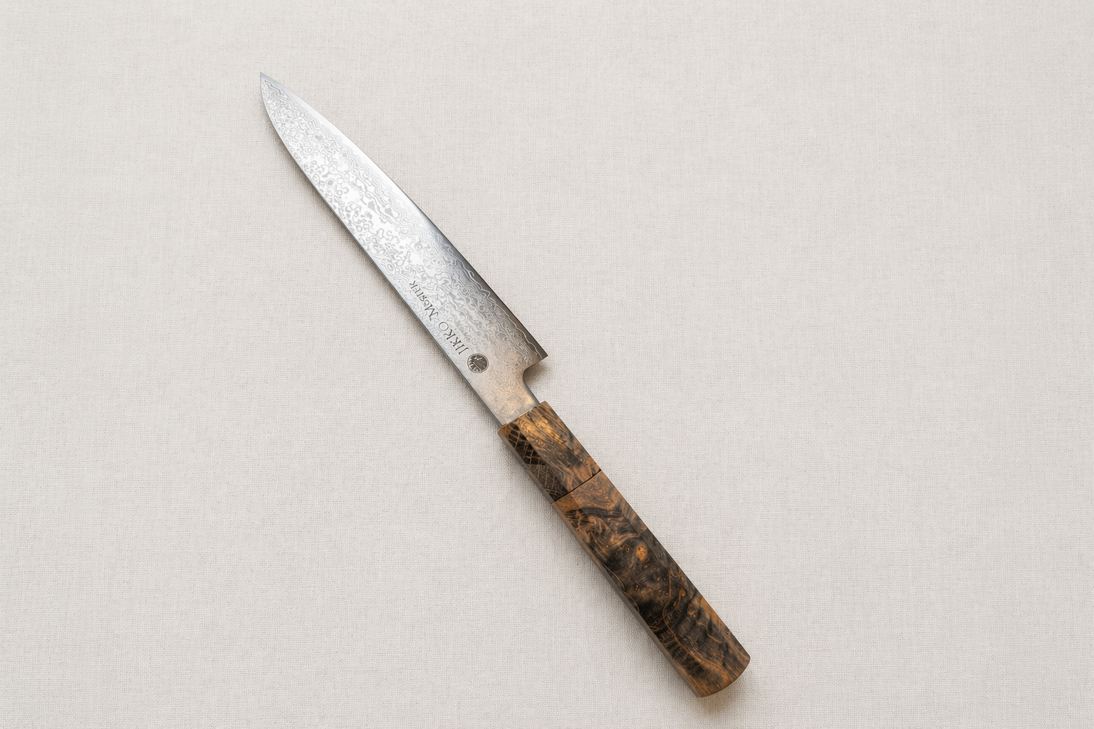 白いリネンと自然光の中で輝く、實光のダマスカスペティナイフ