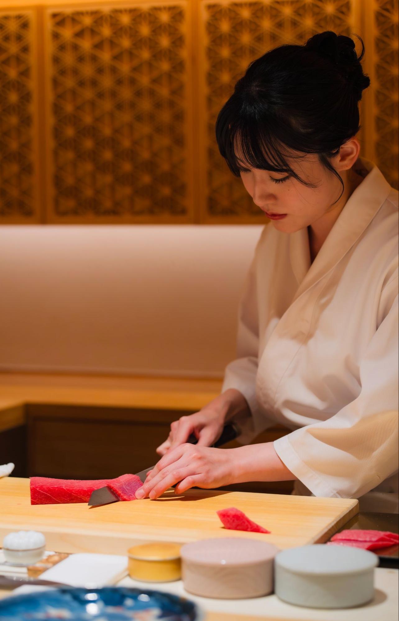鮨六式のカウンターで真剣な眼差しで魚と向き合う女性鮨職人、井上氏