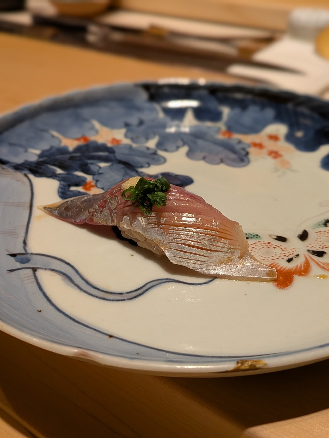鮨六式で提供される、細かい切れ目が入り浅葱と生姜が添えられた美しい鯵の握り