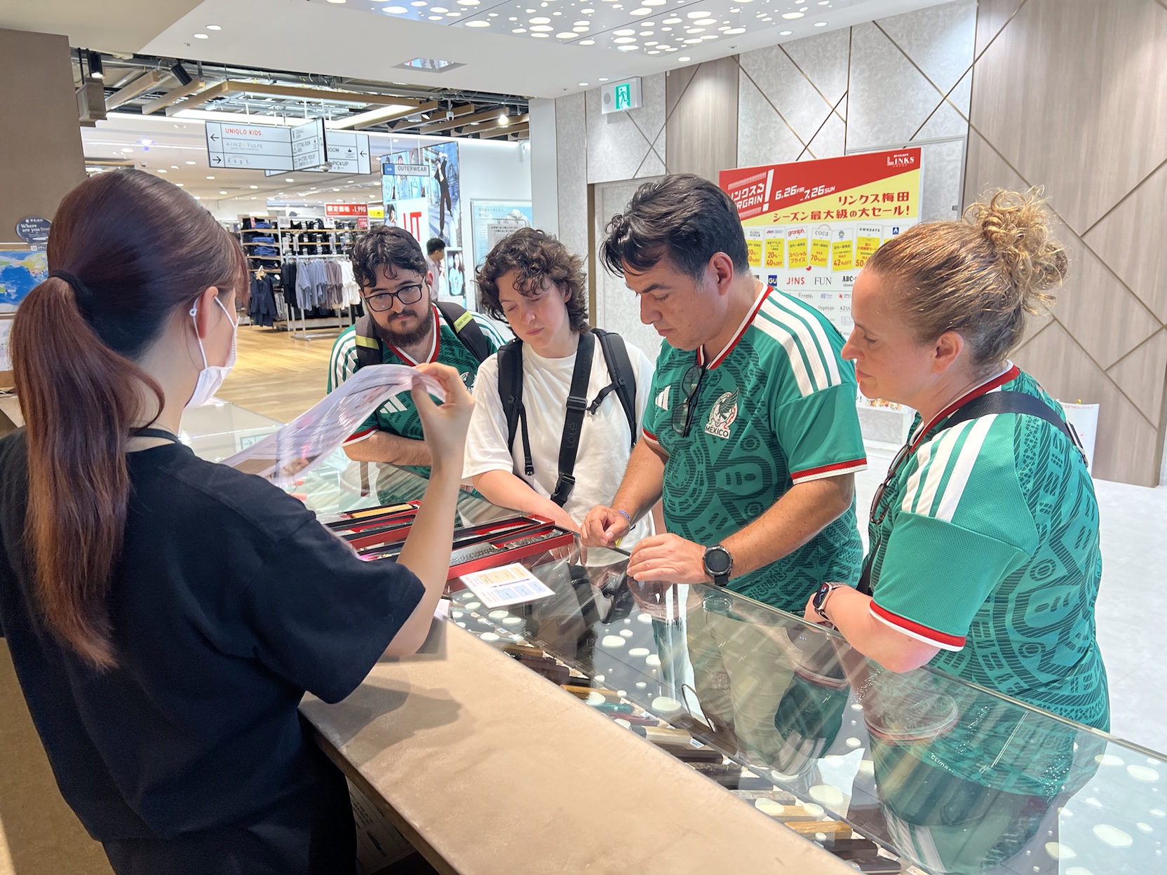 海外から来店されたお客様に、日本料理で使われる片刃包丁の特徴や用途を説明する實光スタッフ。店頭での会話を通して、日本の包丁文化を伝えている接客風景。